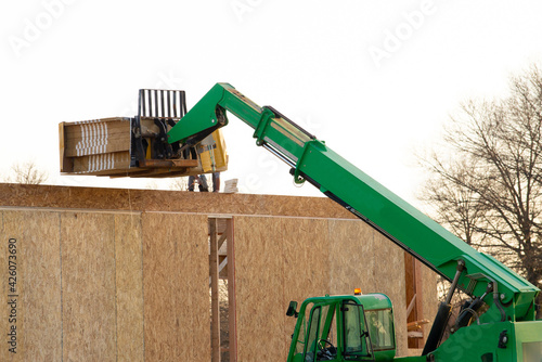 Bild auf Leinwand forklift at a construction site of a plywood house wood new frame