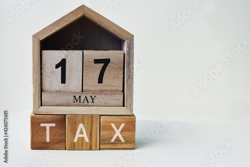 Tax Day concept with wooden calendar 17 May and cube, copy space text.