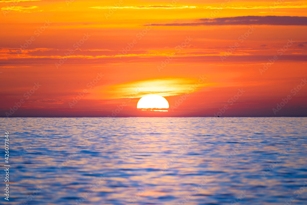 Sun rising in the sea. Beautiful sunrise on the ocean with a big and colorful sun in summer. A new day begins.