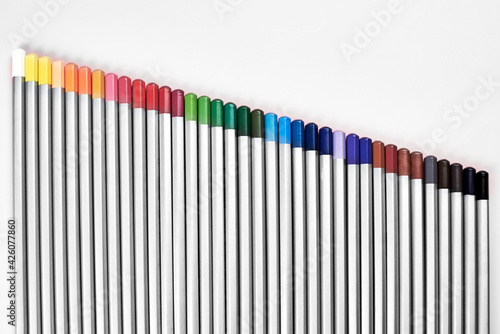 Colored pencils lined up in a row on a pink background.