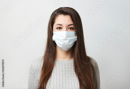 Young woman wearing medical mask, white background.