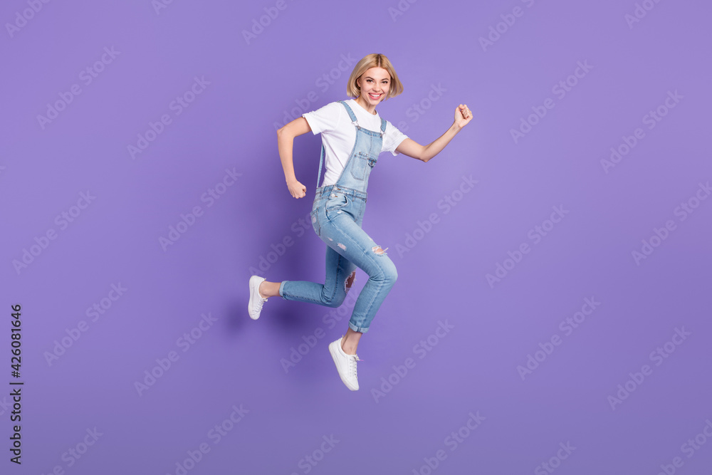 Full size profile photo of nice optimistic short hairdo blond lady run wear white t-shirt overall isolated on violet background