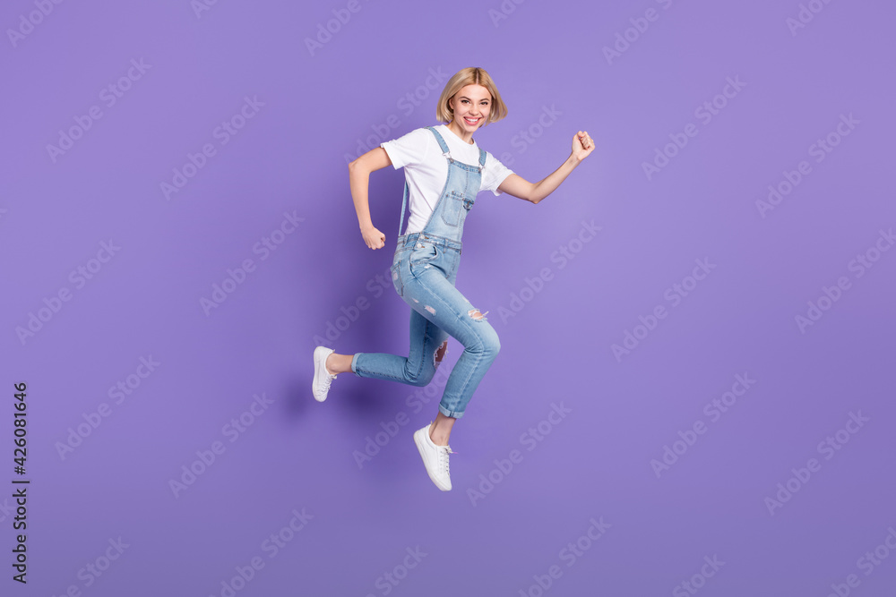 Full size profile photo of nice optimistic short hairdo blond lady run wear white t-shirt overall isolated on violet background Full size profile photo of nice optimistic short hairdo blond lady run wear white t-shirt overall isolated on violet background