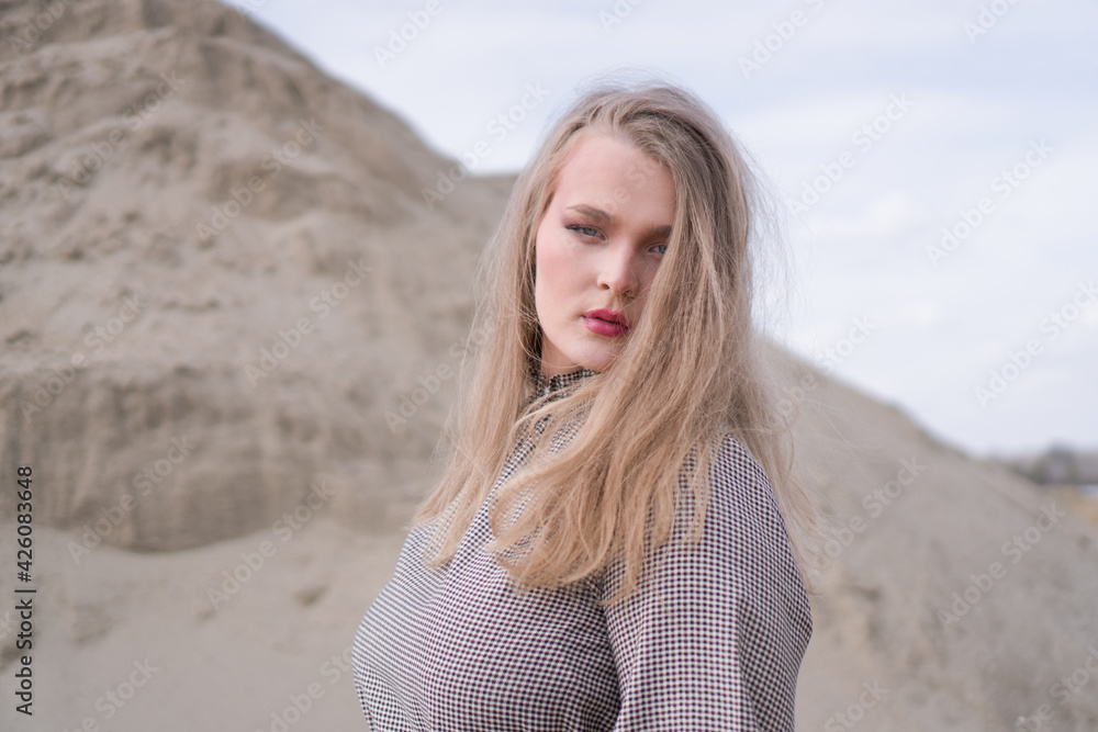Beauty portrait of a young blond girl in a vintage dress. She is posing on a sandy landscape. Beauty portrait of a young blond girl in a vintage dress. She is posing on a sandy landscape.