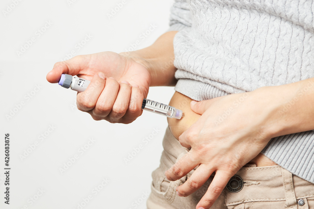 Young woman doing insulin injection pen, close-up.