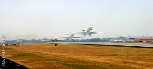 Composite images, airliner taking off concept. Hazy grey sky on a cloudy day. Spring grass, yellow and brown along the runway.