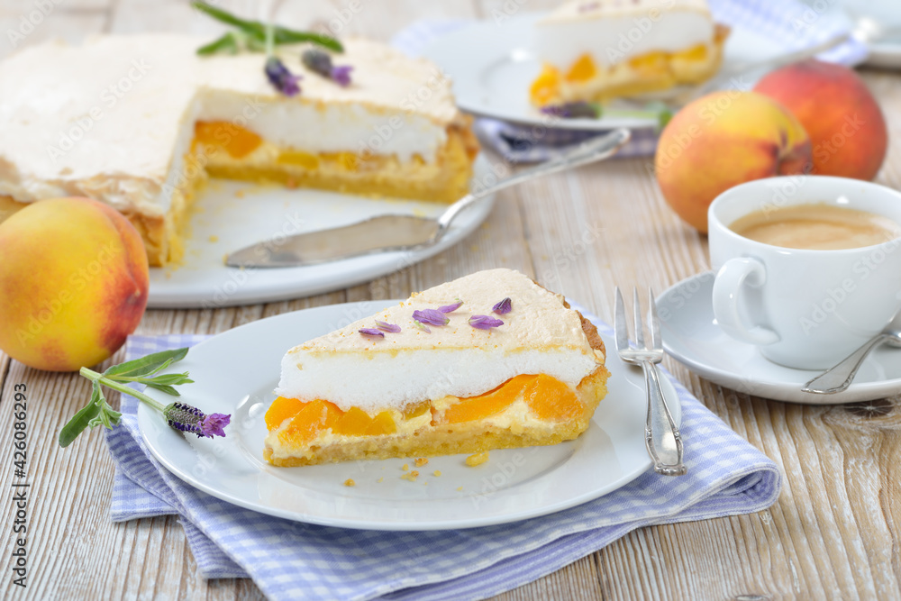 Leckerer Pfirsich-Tarte mit Lavendelhonig und Baiserhaube sowie einem Cafe Creme auf einem Holztisch mit Deko - Peach pie with lavender honey topped with sweet meringue served with a cup of coffee Leckerer Pfirsich-Tarte mit Lavendelhonig und Baiserhaube sowie einem Cafe Creme auf einem Holztisch mit Deko - Peach pie with lavender honey topped with sweet meringue served with a cup of coffee