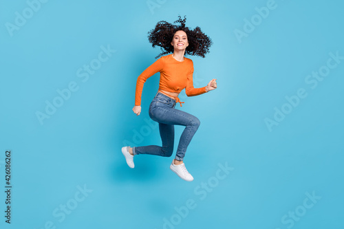 Fototapeta Naklejka Na Ścianę i Meble -  Full length body size photo of woman with curly hair running fast on sale jumping isolated vivid blue color background