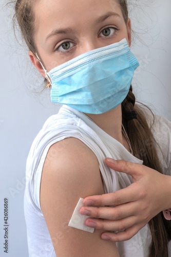 girl in a medical mask holds cotton wool on her hand after the injection. The concept of medicine and vaccination
