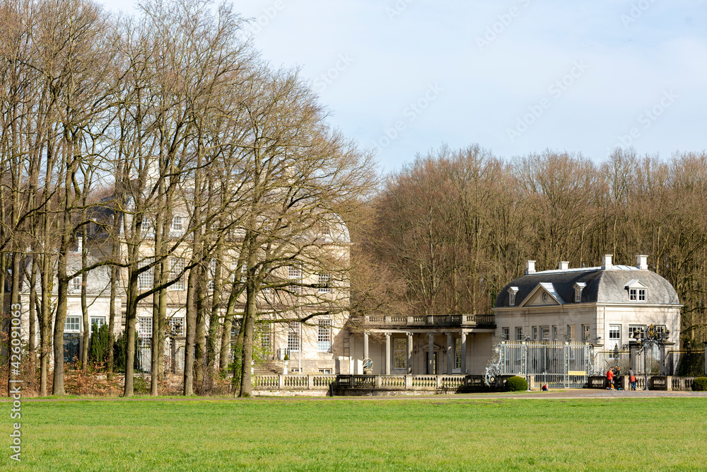 Sideview of picturesque moated manor castle Huis de Voorst with a seperate house seen through tall winter barren trees Sideview of picturesque moated manor castle Huis de Voorst with a seperate house seen through tall winter barren trees