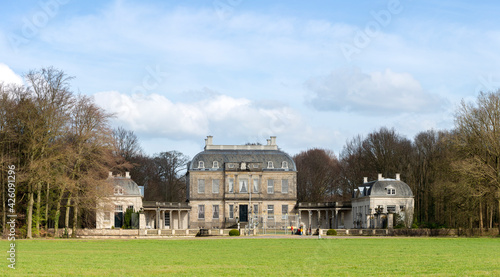Fototapeta Naklejka Na Ścianę i Meble -  Blue sky and clouds above picturesque panorama of Huis de Voorst mansion surrounded by trees and green meadow in front in Dutch city Zutphen, The Netherlands