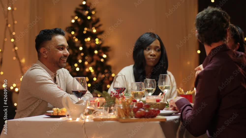 winter holidays, celebration and people concept - happy friends having christmas dinner at home and giving presents winter holidays, celebration and people concept - happy friends having christmas dinner at home and giving presents