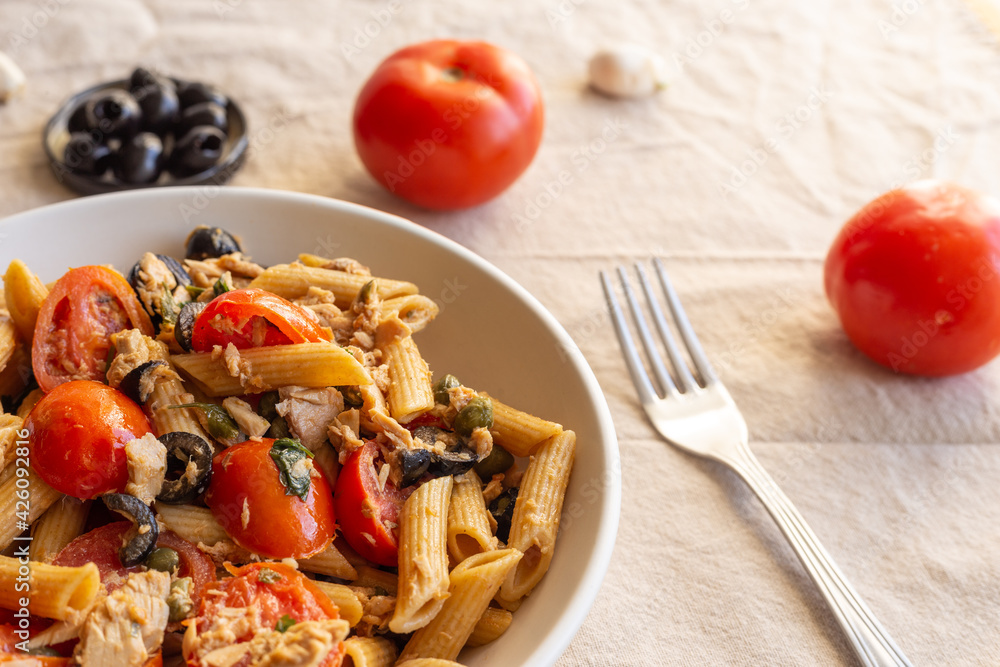 Penne pasta with tuna, capers, tomato and black olives. Typical italian dish. Penne pasta with tuna, capers, tomato and black olives. Typical italian dish.