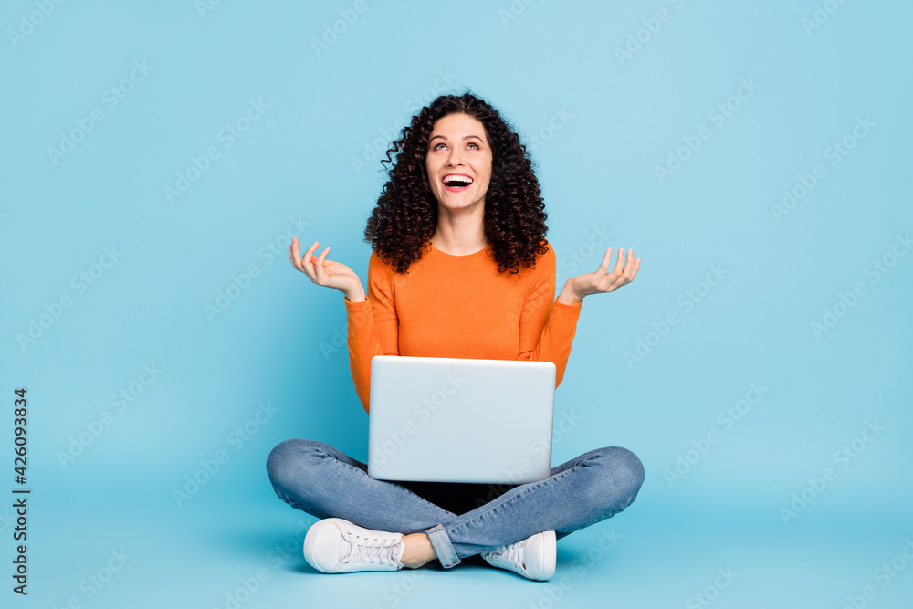 Full length body size photo of female freelancer with computer laughing looking up isolated on vibrant blue color background Full length body size photo of female freelancer with computer laughing looking up isolated on vibrant blue color background
