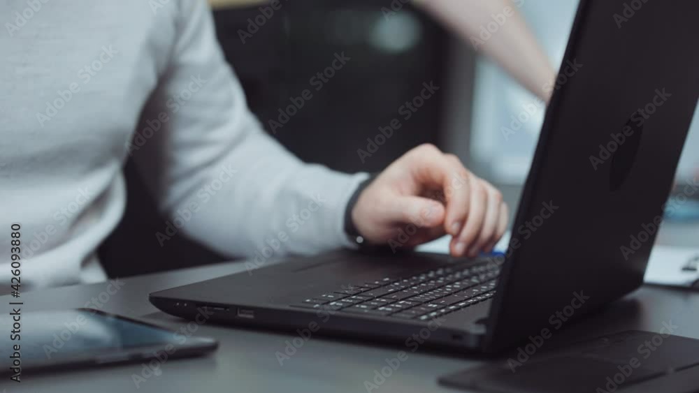 Male hands typing on laptop and using tablet. Closeup businessman looking at wrist watch while preparing report, blurred colleague on background. Concept of deadline Male hands typing on laptop and using tablet. Closeup businessman looking at wrist watch while preparing report, blurred colleague on background. Concept of deadline