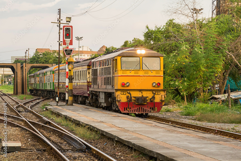 Naklejka premium Locomotive train on railroad tracks from Thailand go into train station. Transport move passenger to station. Railway Tracks at a Major Train Station. traditional transport.