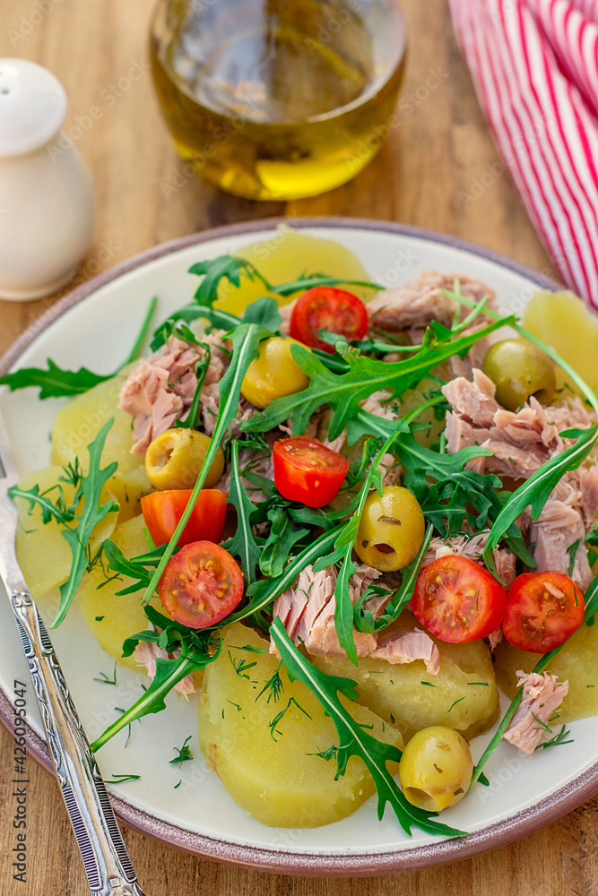 Potato salad with tuna, cherry tomatoes, olives and arugula