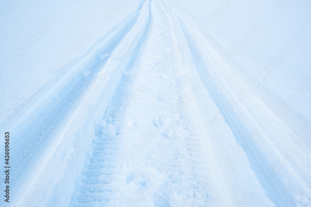 Snowmobile tracks in deep snow. Twisting traces of a snowmobile crossing snow covered field Snowmobile tracks in deep snow. Twisting traces of a snowmobile crossing snow covered field