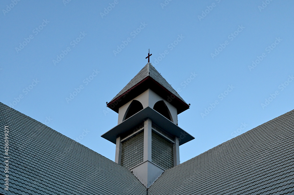 Church Roof with a cross. Church building roof with holy cross. Cloudy moody blue sky background. Minimal architecture design and detail. Exterior design and detail. 