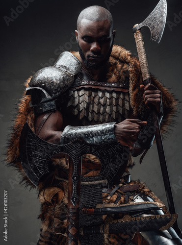 Northern african chief with fur wielding dual axes in dark background