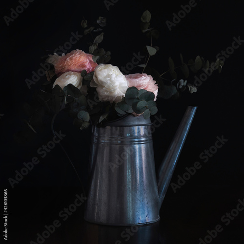 Flowers in a watering can, looking like an old still life painting, vintage and shabby mood