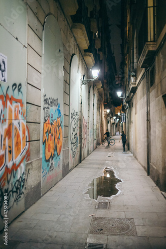 A narrow hallway with graffiti on the side of a building