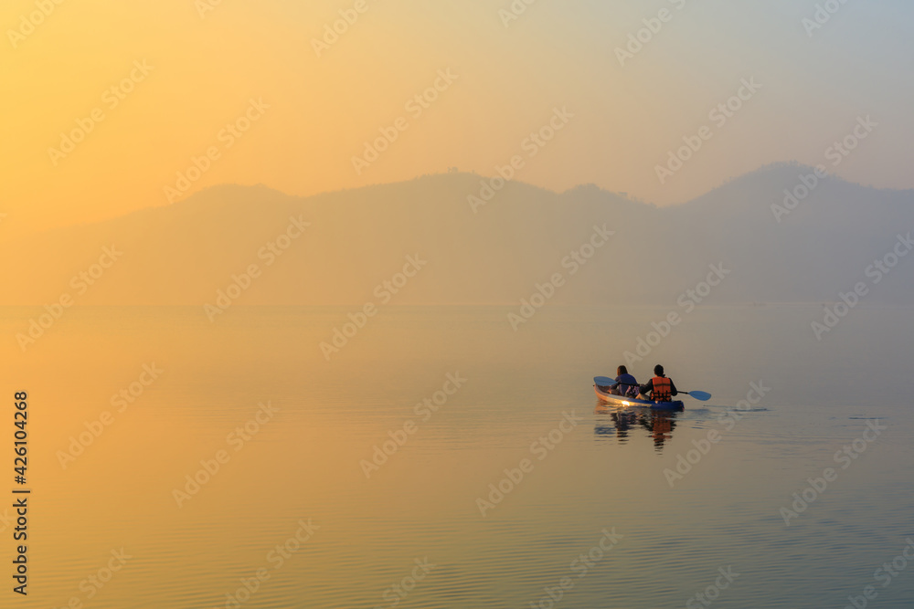 Sunrise time at lake or river with small kayak boat with mountain on the background.