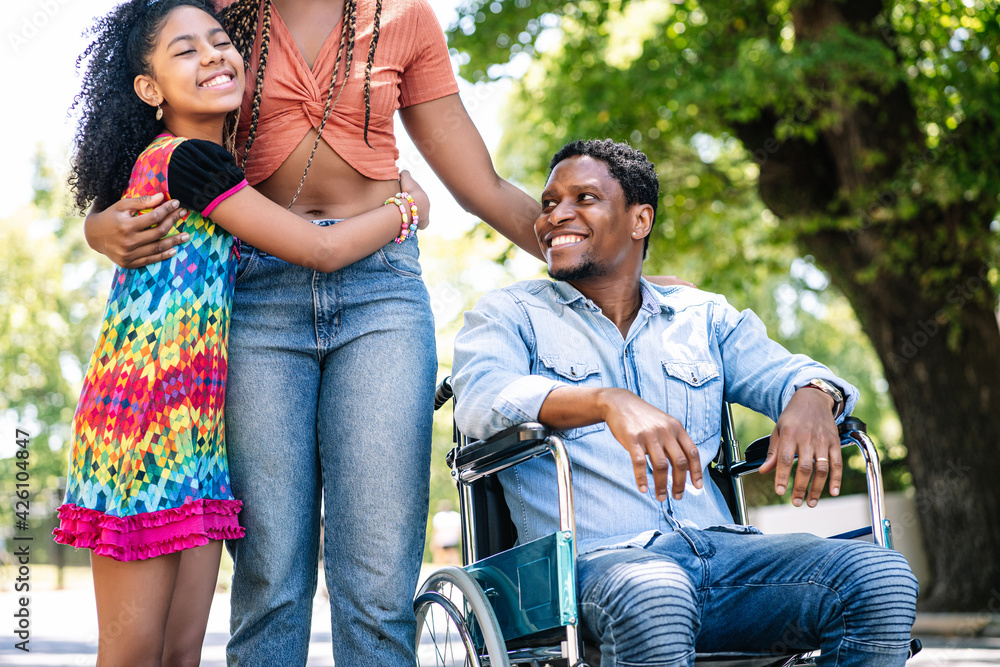 Man in a wheelchair enjoying a walk outdoors with family. Man in a wheelchair enjoying a walk outdoors with family.