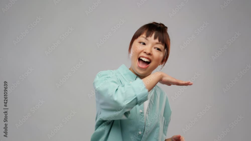 happiness and people concept - happy smiling asian woman dancing over grey background happiness and people concept - happy smiling asian woman dancing over grey background