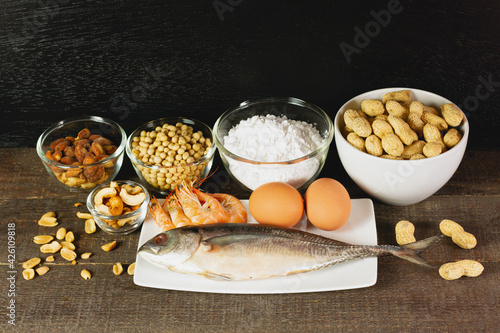 Major food allergens include egg, penuts, fish, shrimp, wheat flour, soya, almond and cashew nut on rustic wooden table. Allergy food concept.