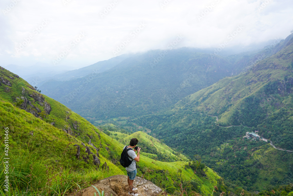 Young man taking pictures of a huge valley in mini Adams Peak, Sri Lanka.