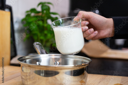 Pouring milk into a pot. Preparation of béchamel sauce.