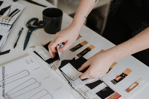 Fototapeta Young businesswoman and fashion designer reviewing her clothes design sketches