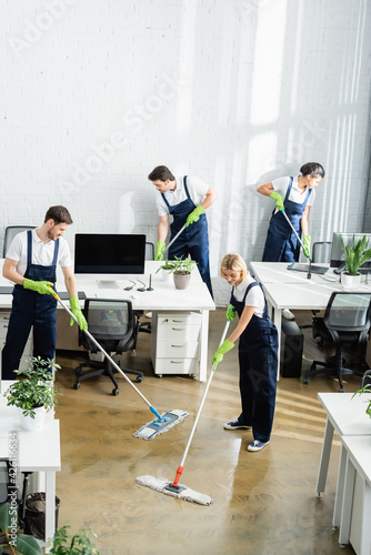 Multiethnic cleaners washing floor in modern office