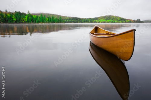 United States, New York, Saranac Lake, Wooden canoe floating on calm Upper Saranac Lake photo