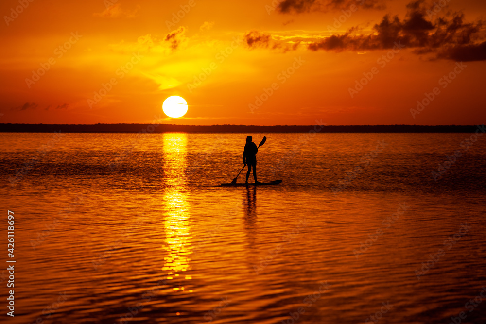 Stand up paddling into the sunset on the ocean