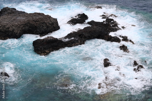 Turquoise ocean waves crashing against the rocks. Bird s eye view of the ocean water  from above.