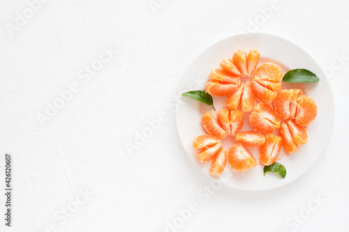 Tangerine slices on plate and textured white background