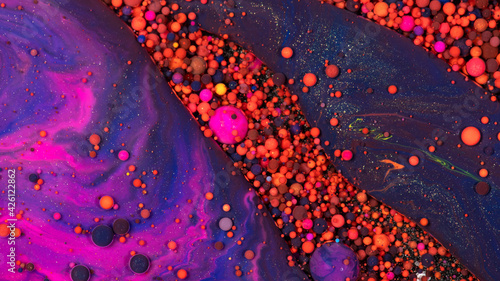 Abstract background of bobbly and mixed orange, purple and pink oily paints photo