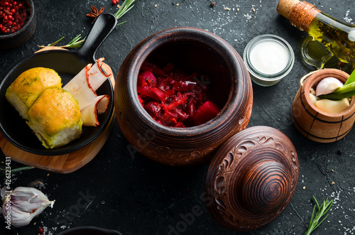 Ukrainian food. Borsch with lard, garlic and donuts on a black stone background. Top view. Rustic style.
