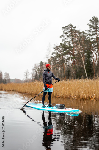 Young men paddle with SUP or stand up paddle board in small river. concept of harmony with the nature. Stand up paddle boarding - awesome active outdoor recreation.