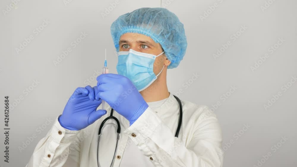 A young handsome doctor prepares for vaccination, prepares a syringe with a vaccine before an injection.Doctor's hands fill the syringe with vaccine, preparing for the injection of the injection to A young handsome doctor prepares for vaccination, prepares a syringe with a vaccine before an injection.Doctor's hands fill the syringe with vaccine, preparing for the injection of the injection to