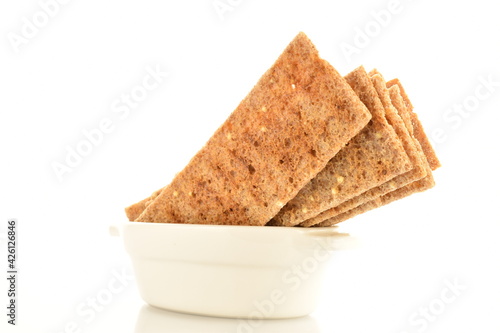 фотографія Several multigrain thin crisps in a white ceramic bowl, close-up, isolated on white