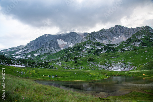 panoramic view of the mountain lake with tourist tents a cloudy summer day. Adygea, Russia.