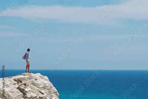 Man standing on the rock and looking to the turquoise sea