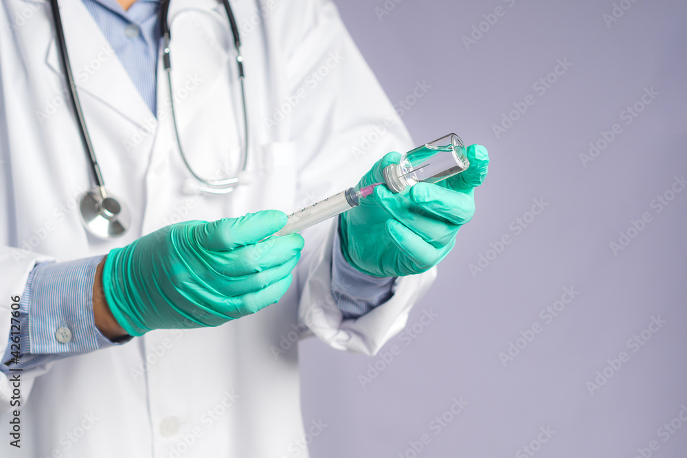 A doctor holding a syringe and COVID-19 vaccine bottle. Vaccine for immunization, and treatment from coronavirus infection. Front view. Concept of medical and the fight against coronavirus A doctor holding a syringe and COVID-19 vaccine bottle. Vaccine for immunization, and treatment from coronavirus infection. Front view. Concept of medical and the fight against coronavirus