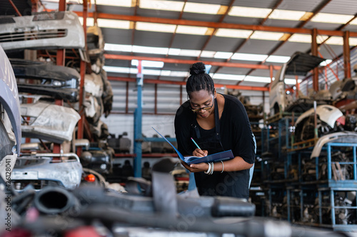 African american worker woman wear spectacles make a note of the product list on clipboard in factory auto parts. female employee business warehouse motor vehicle.