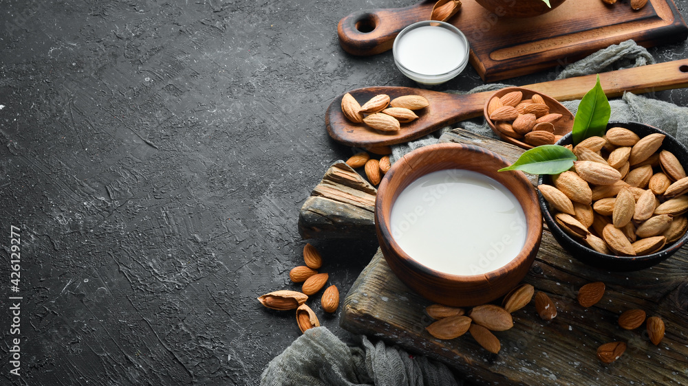 Almond milk and almonds on black stone background. Top view. Free space for your text.