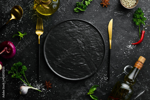Fototapeta Naklejka Na Ścianę i Meble -  Cutlery and black plate on a black stone background. Top view. Free space for text.