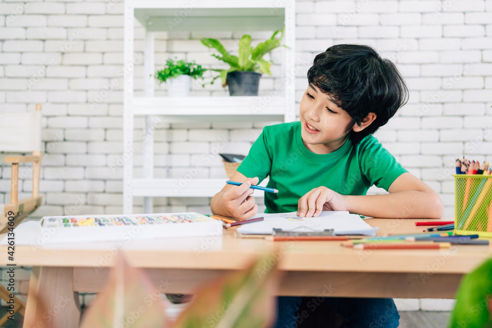 The child's drawing with colored pencils on white paper with smiling on a wooden table. Children's creativity expressed through art in kindergarten and elementary school. back to school. The child's drawing with colored pencils on white paper with smiling on a wooden table. Children's creativity expressed through art in kindergarten and elementary school. back to school.